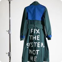 Long coat in forrest green with a bright blue panel on the back with writing fix the system not me in white